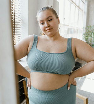 A woman wearing a blue sports bra and matching leggings, standing confidently